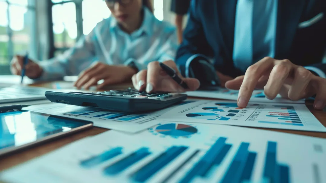 Business team analyzing income charts and graphs with calculator and tablet.
