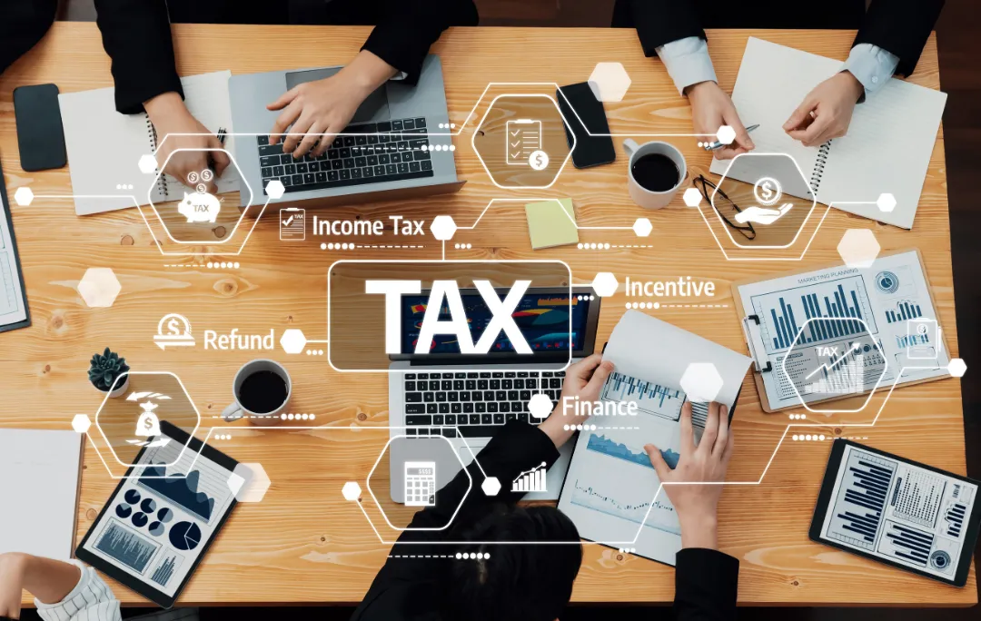 Engaging business meeting scene exploring tax strategies, showcasing collaboration with various documents, charts, laptops, and coffee cups in a modern workspace, focusing on finance.